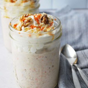 side view of carrot cake oats in mason jars with two spoons laying next to the jars