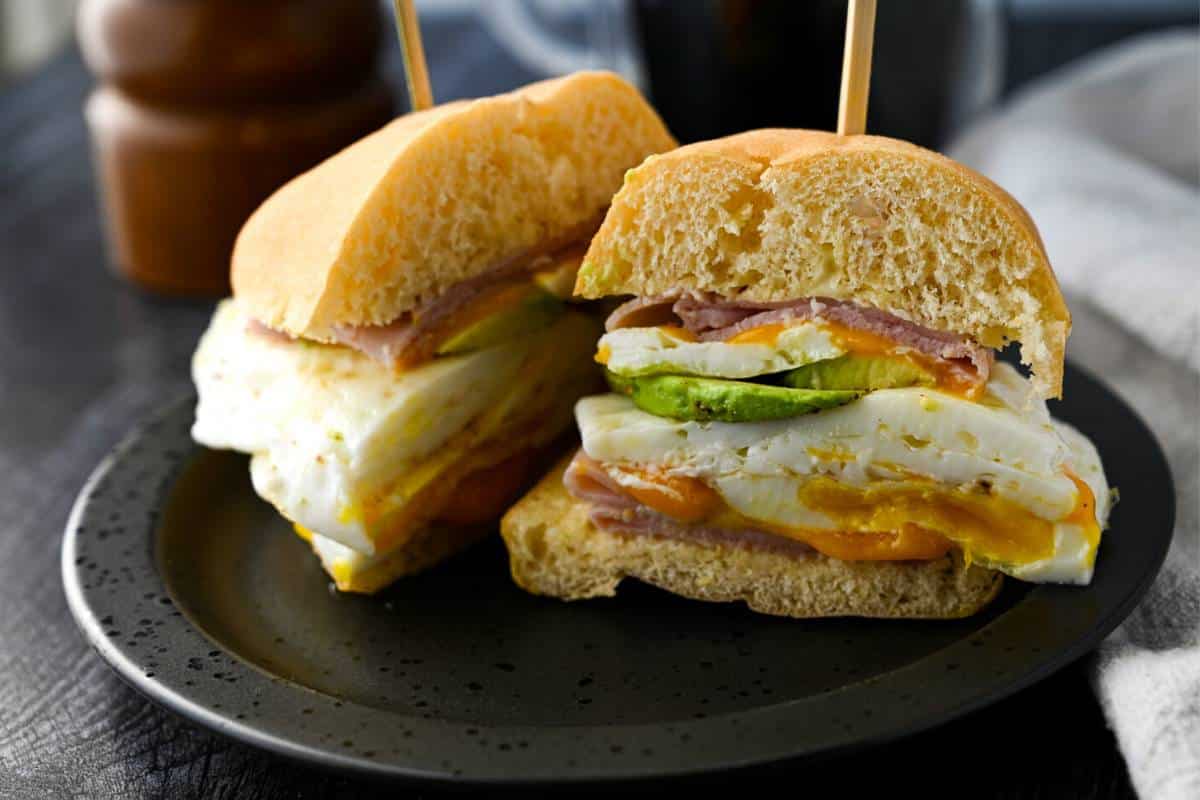a gluten free breakfast sandwich sliced in half with a sandwich pick on top