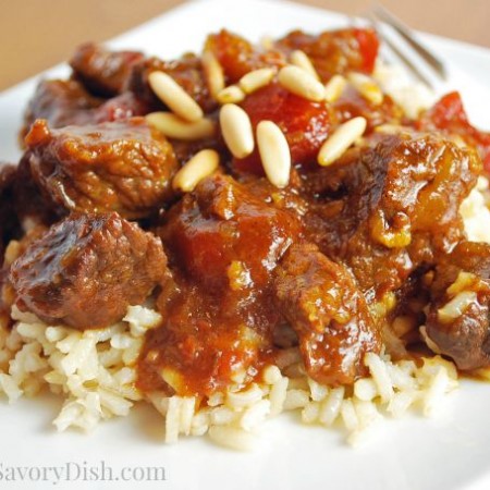 Marrakesh beef over rice topped with pine nuts on a plate with a fork