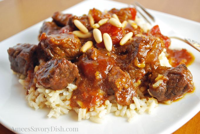 Marrakesh beef over rice topped with pine nuts on a plate with a fork