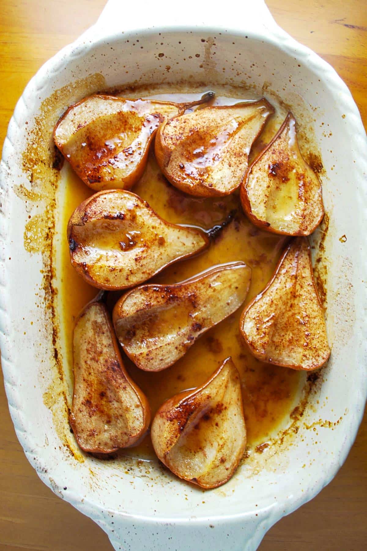 a baking dish with baked pears sprinkled with cinnamon and baked with butter and maple syrup