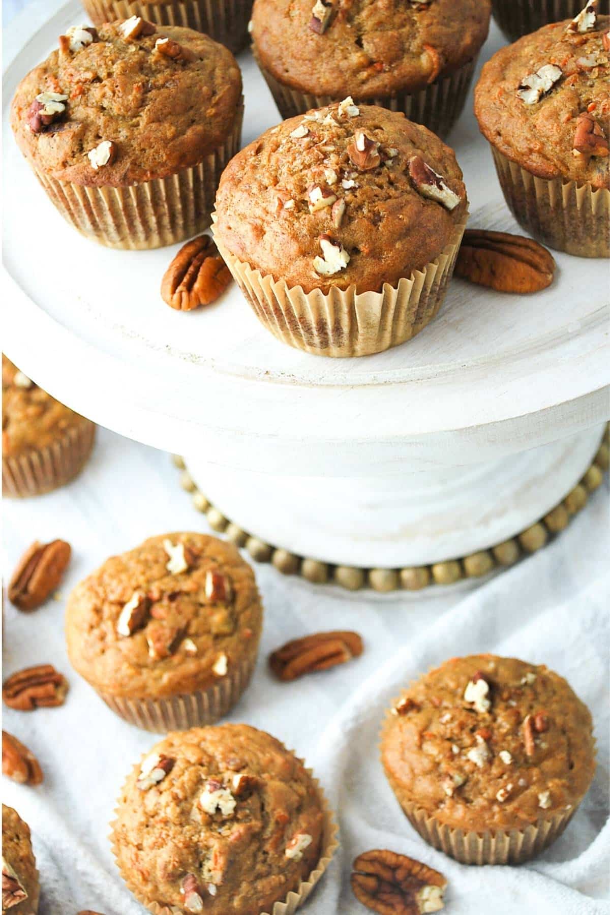 banana carrot muffins on a white platter with muffins on the table below