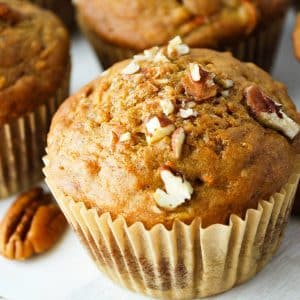 close up photo of a banana carrot muffin topped with chopped nuts