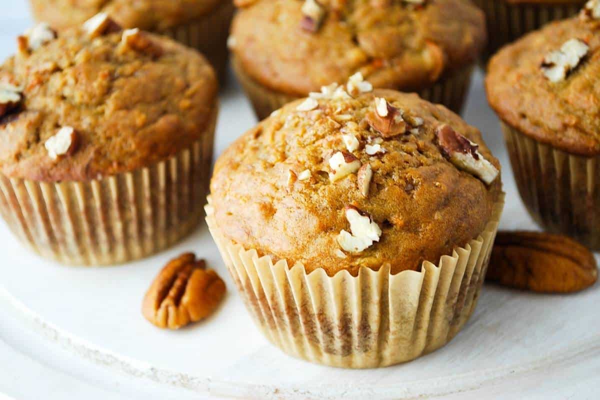 muffins topped with pecans on a platter with whole pecans