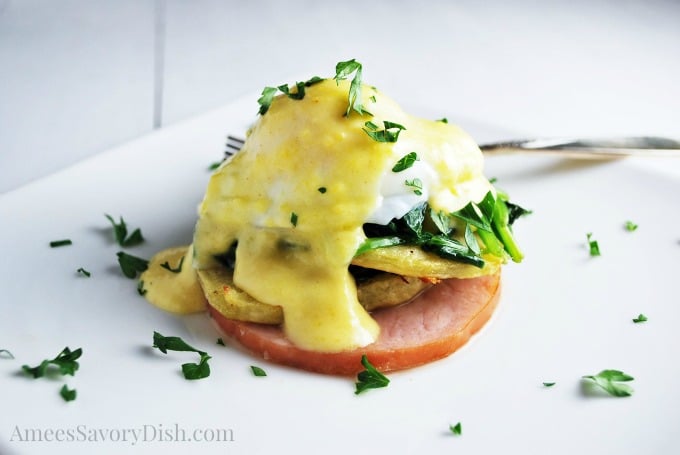 Eggs benedict on a plate dripping with hollandaise
