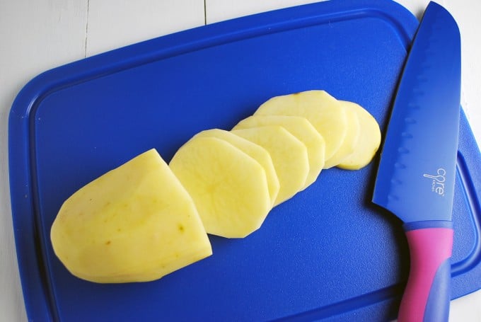 Sliced raw potatoes on a blue cutting board