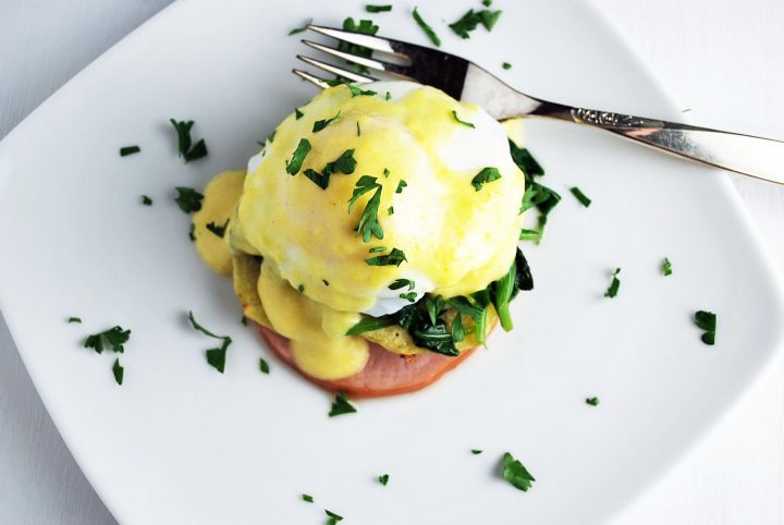 overhead shot of eggs benedict on a plate with fork