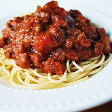 close up photo of spaghetti noodles topped with meat sauce in a bowl