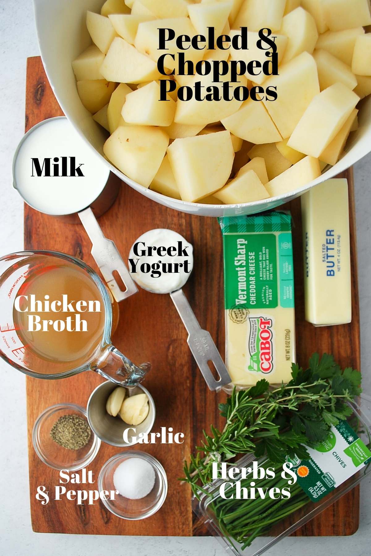 ingredients for loaded potatoes: potatoes, milk, Greek yogurt, chicken broth, garlic, cheese, butter, herbs, and salt and pepper