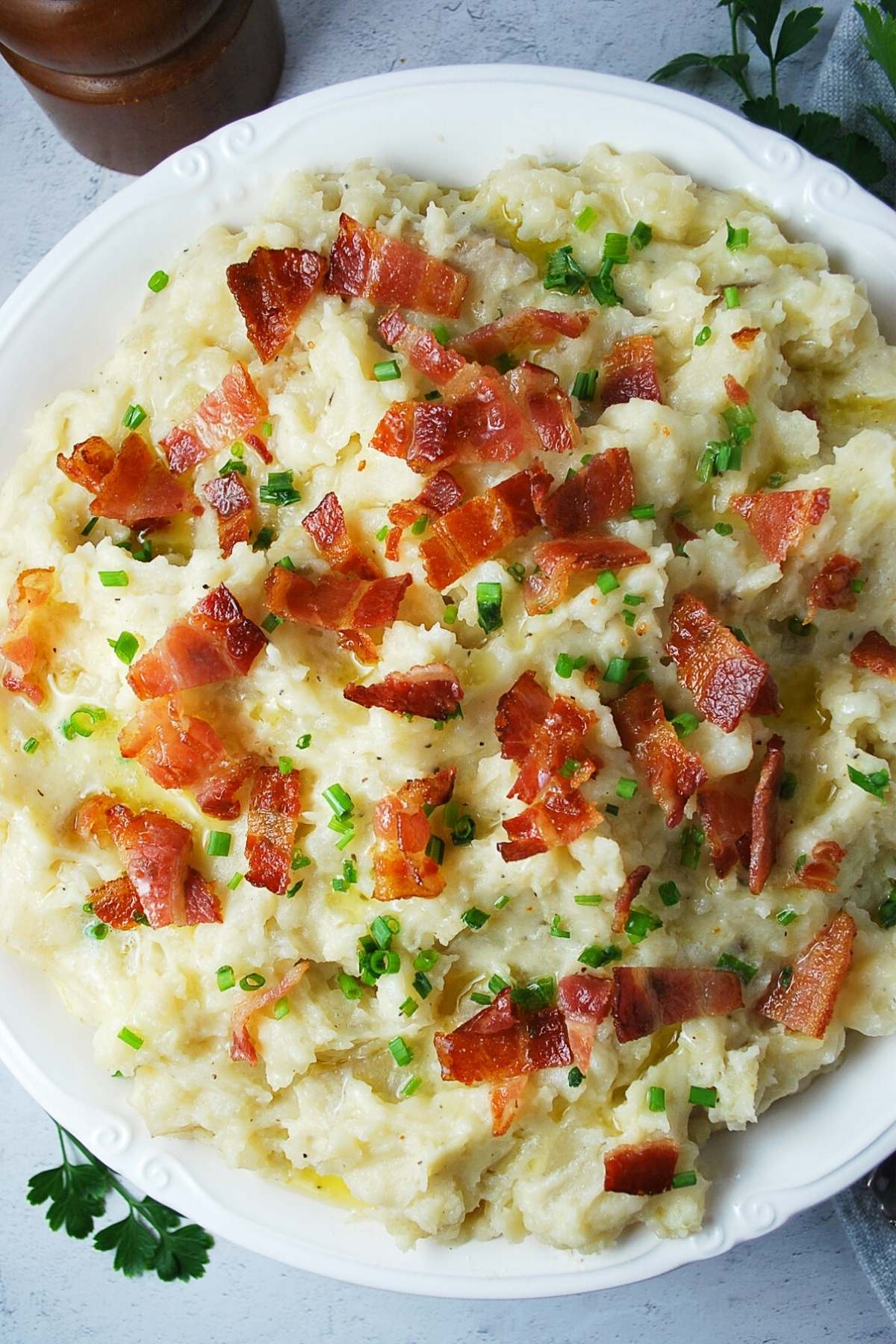 overhead photo of a bowl of loaded mashed potatoes with crumbled bacon and chives on top