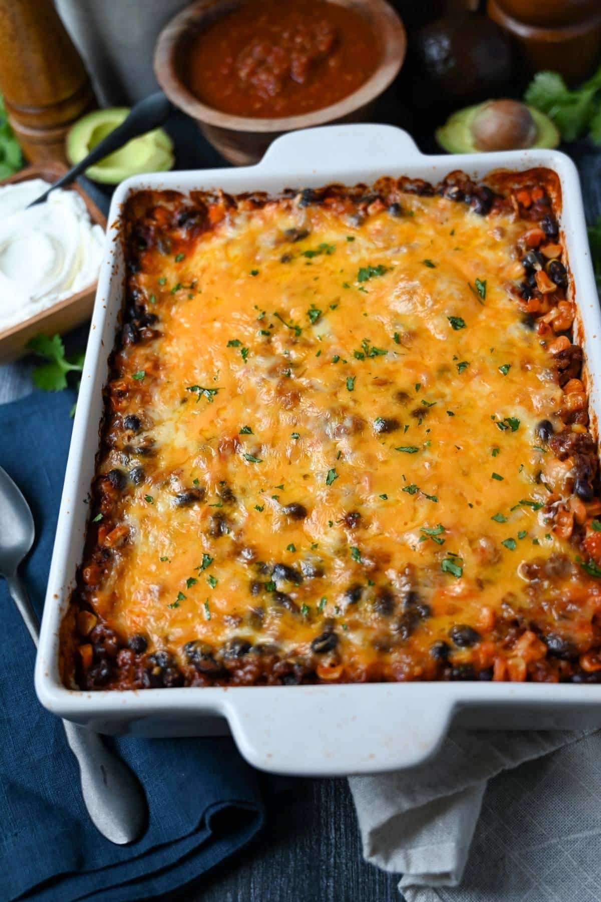 a pan of Mexican beef casserole with sour cream and salsa for serving