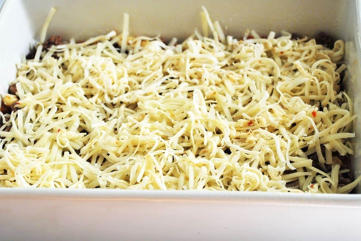 Cheese on top of a layer of meat, black beans and corn in  baking dish