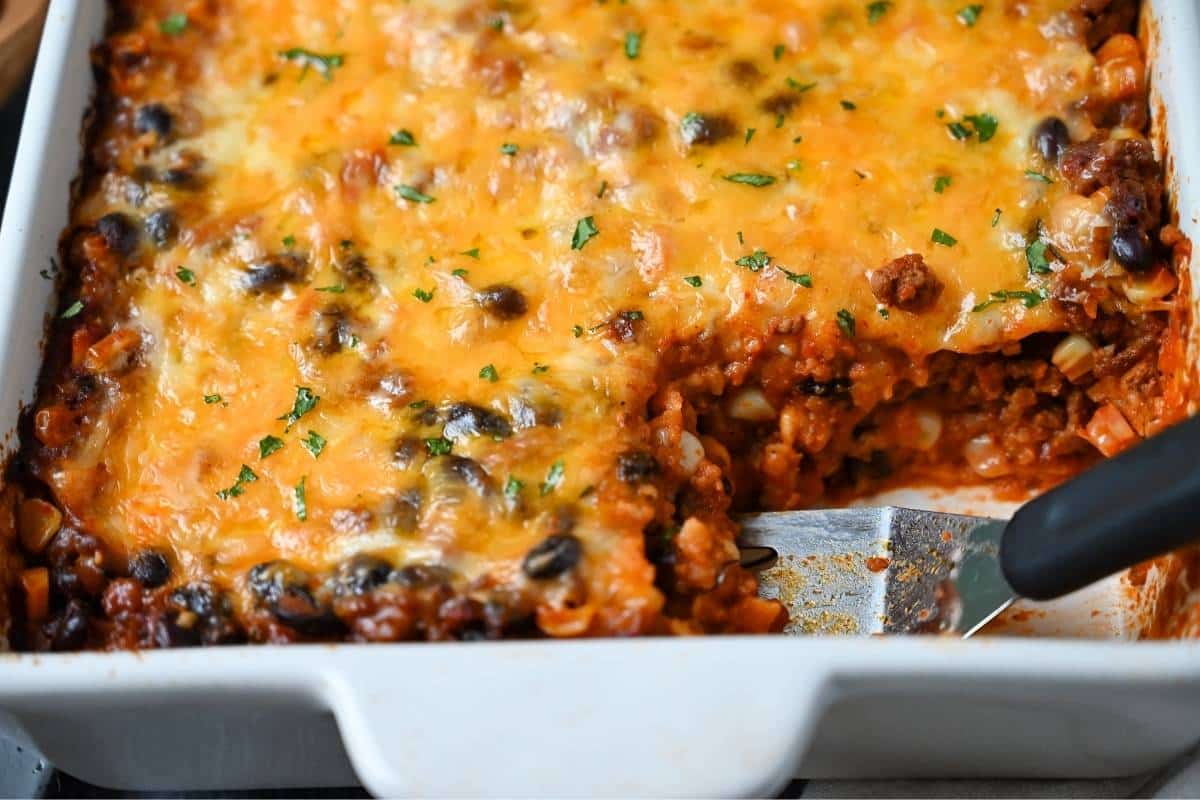 Mexican beef casserole with a slice cut out in a baking dish