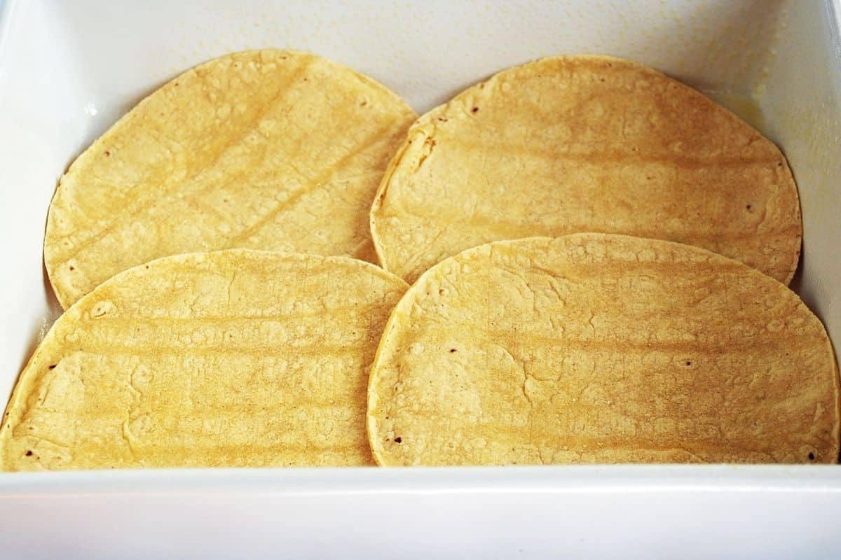 four soft corn tortillas in a baking dish