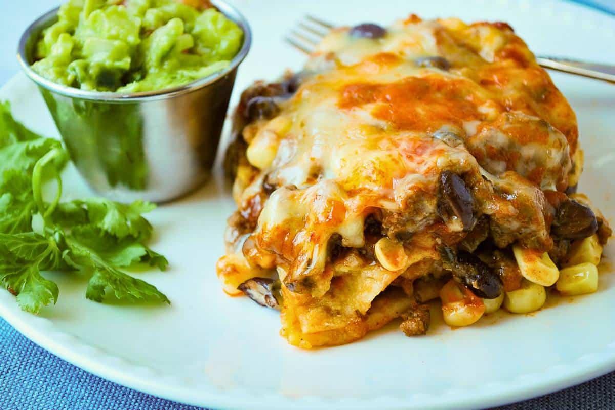 a slice of high protein beef mexican casserole with a dish of guacamole