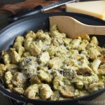 Pesto chicken in a skillet with wooden spoon