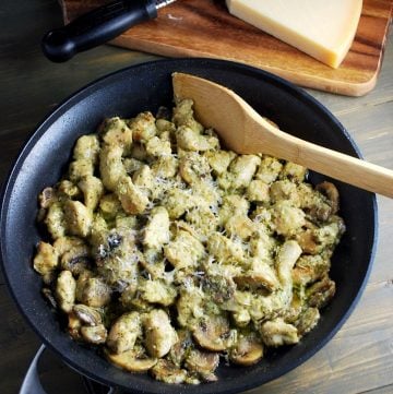 skillet of chicken, cheese, mushrooms and pesto sauce with wooden spatula