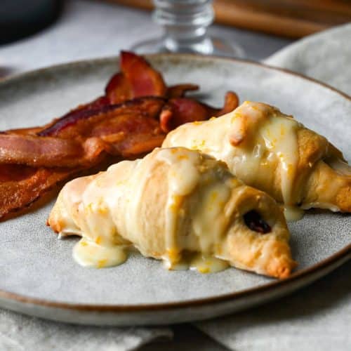 two glazed croissants on a plate with bacon