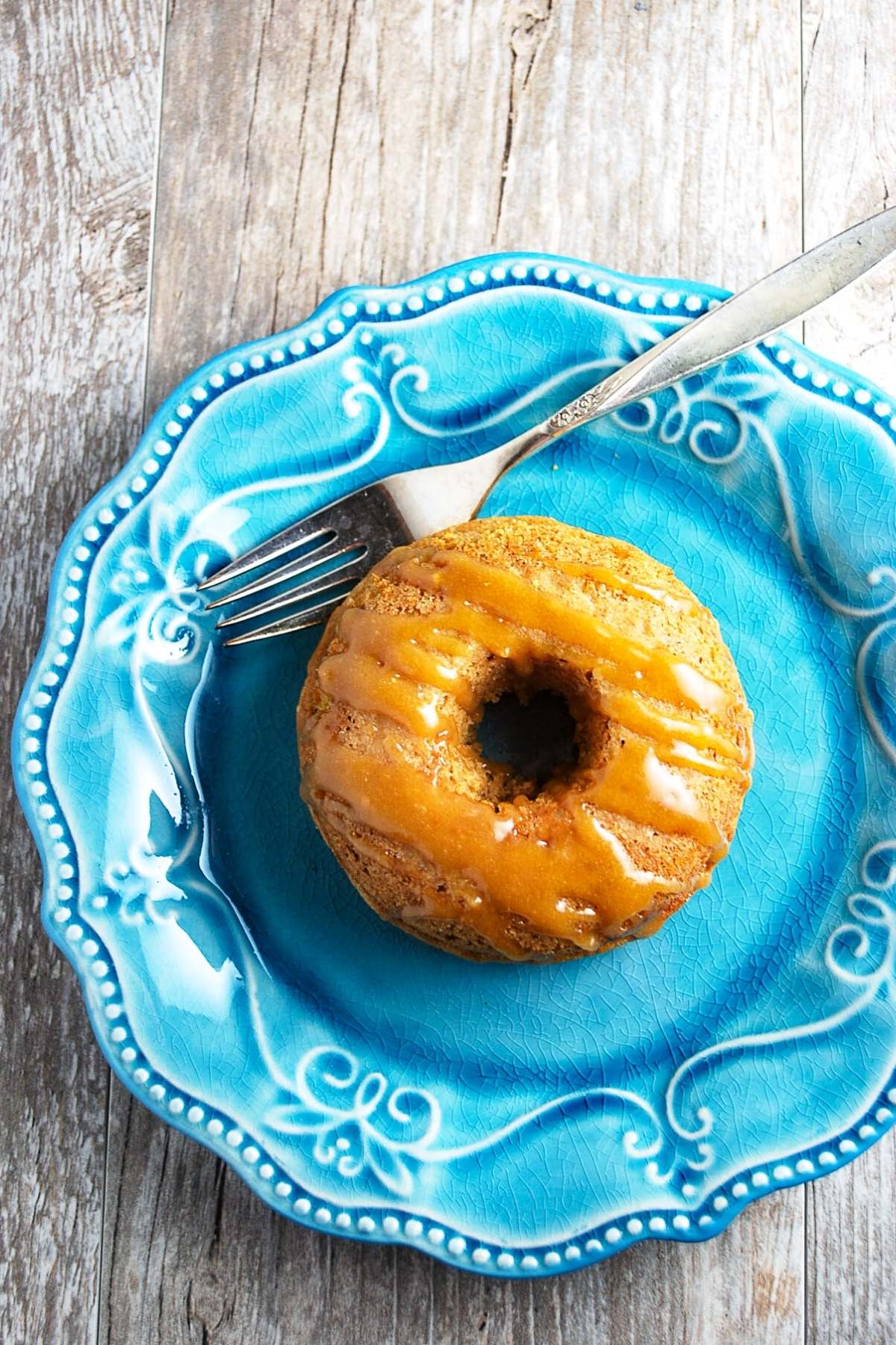 maple donut on a blue plate with a fork