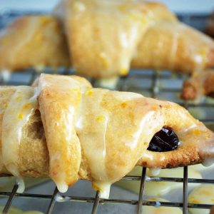 freshly baked croissants dripping with orange glaze on a cooling rack
