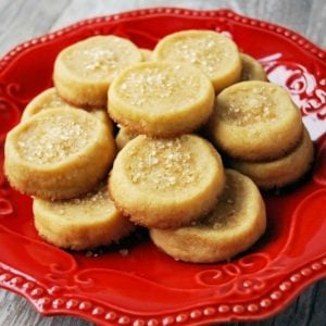 maple shortbread cookies topped with coarse sugar stacked on a red plate