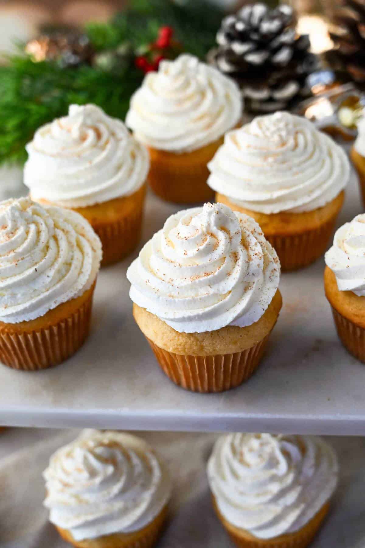 a platter of eggnog cupcake with piped whipped cream frosting 