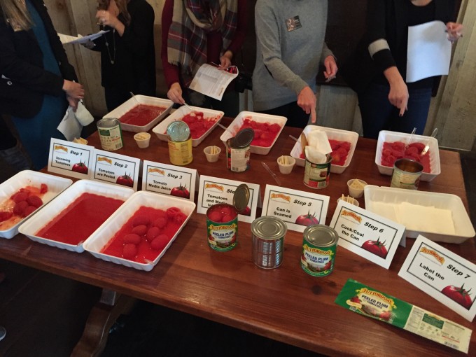 A group of people standing around a table sampling tomatoes