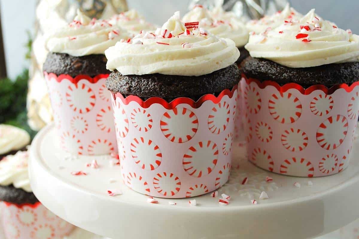 side view of dark chocolate cupcakes with swirled frosting and crushed candy canes on top