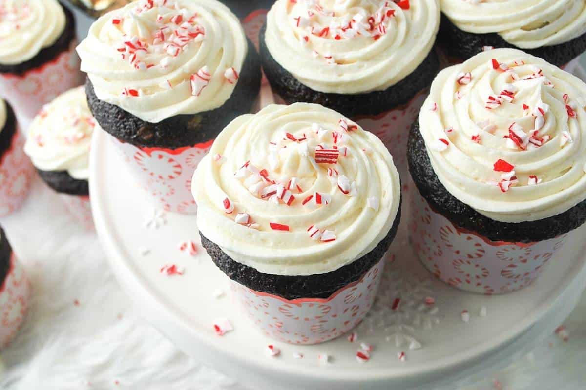 chocolate cupcakes on a white snowflake platter with peppermint sprinkled around them