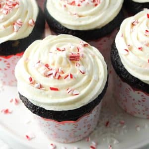 close up of a chocolate cupcake in a cupcake liner with peppermint candies on it with frosting and crushed peppermint on top