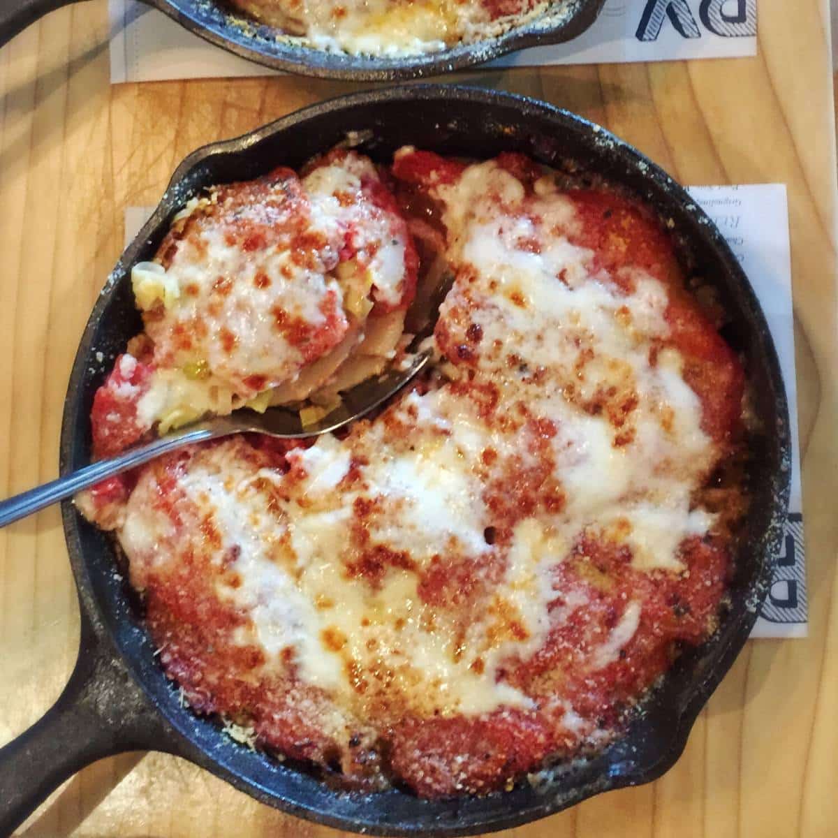 close up of a skillet of baked tomato leek gratin 