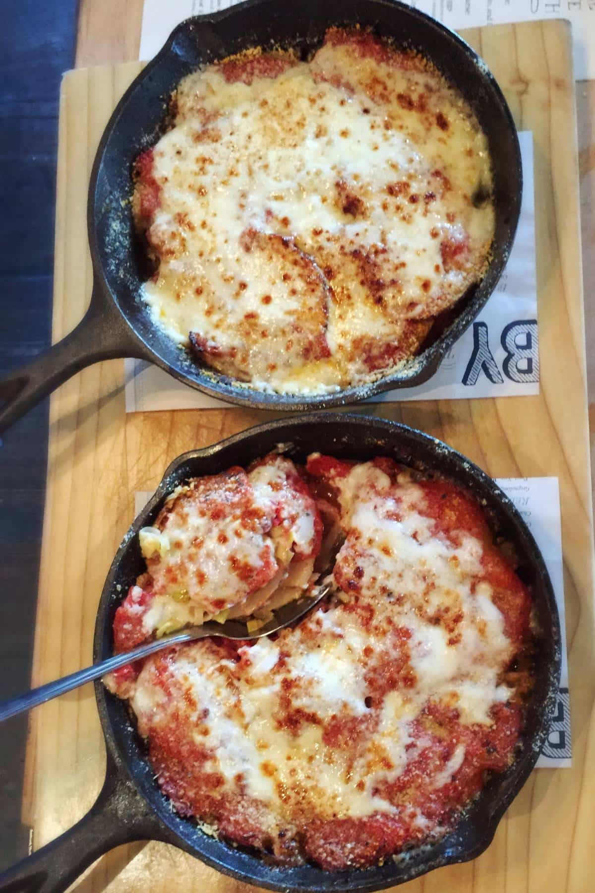 two cast iron skillets with baked tomato potato gratin