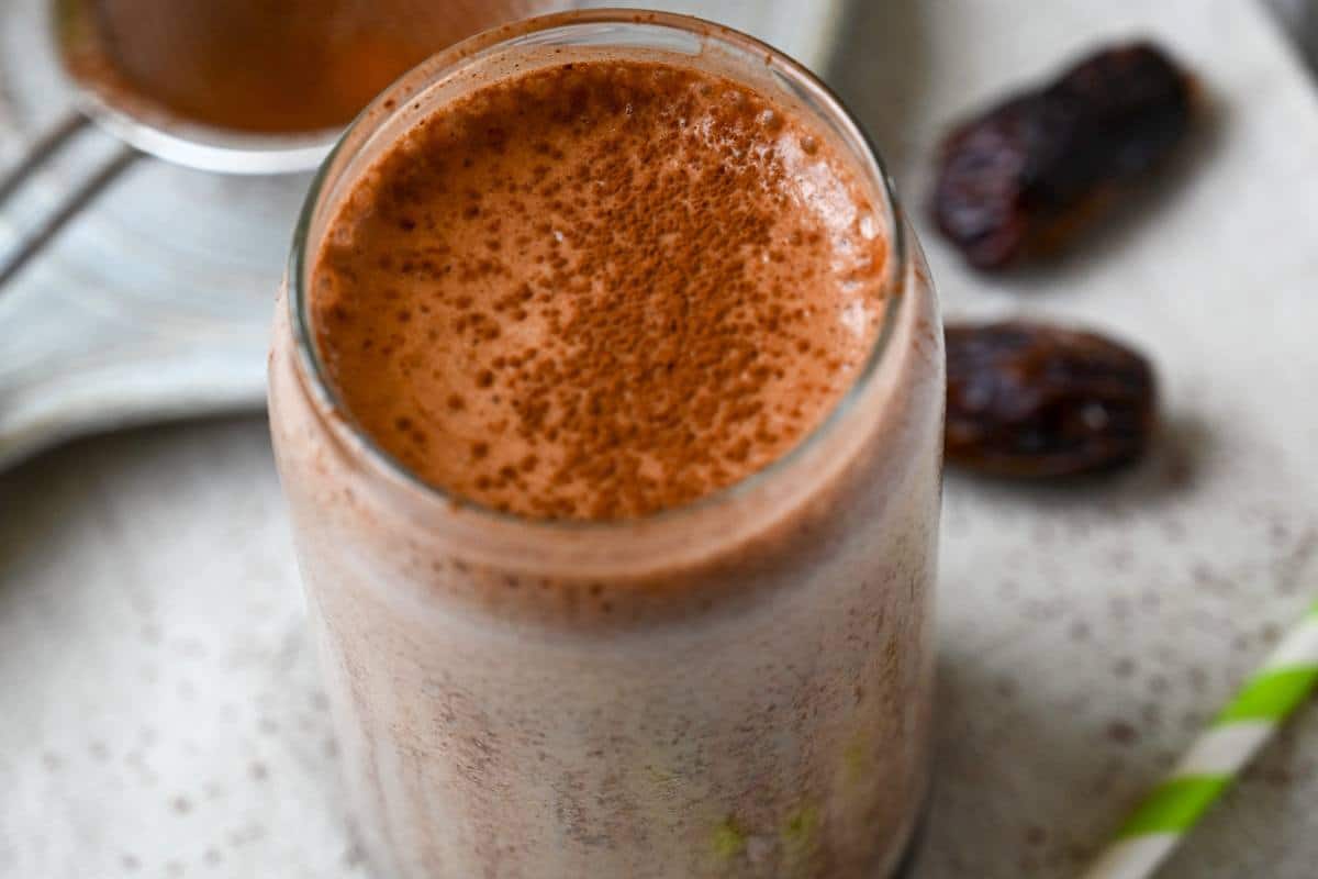 a chocolate shake with cocoa on top in a clear glass