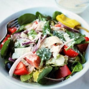 close up of an Italian garden salad in a white bowl with a fork