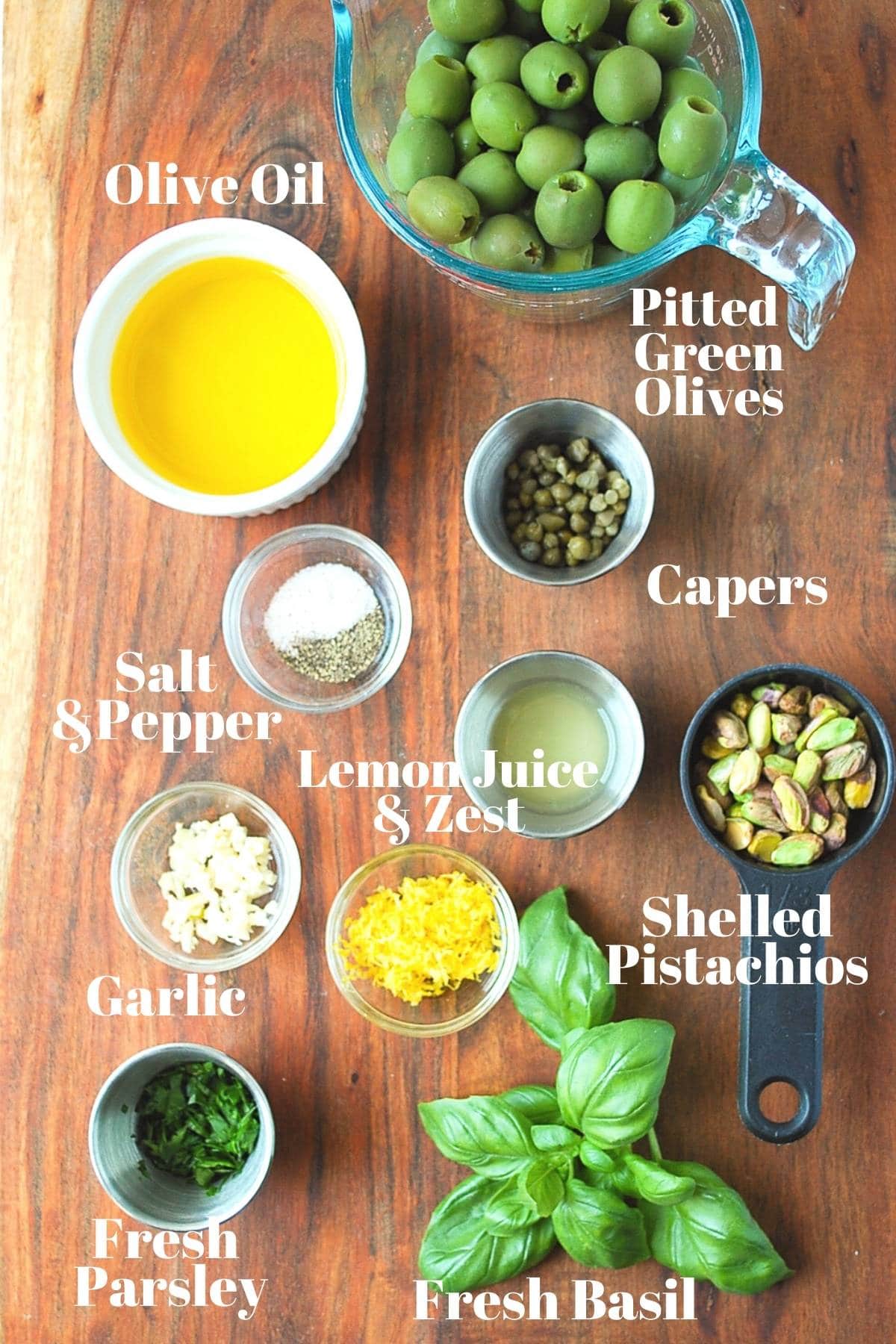 ingredients for green olive tapenade on a cutting board measured out for mixing