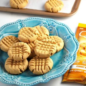 peanut butter cookies on a blue plate with a packet of protein powder next to it