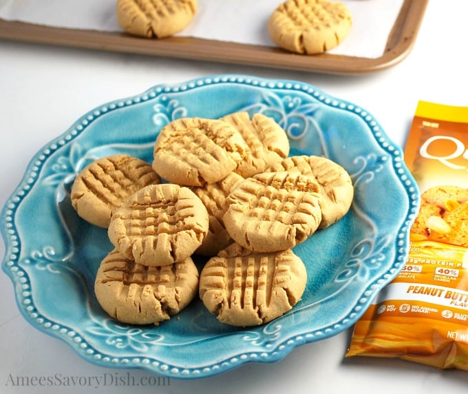 blue plate filled with protein cookies with a packet of Quest peanut butter protein powder