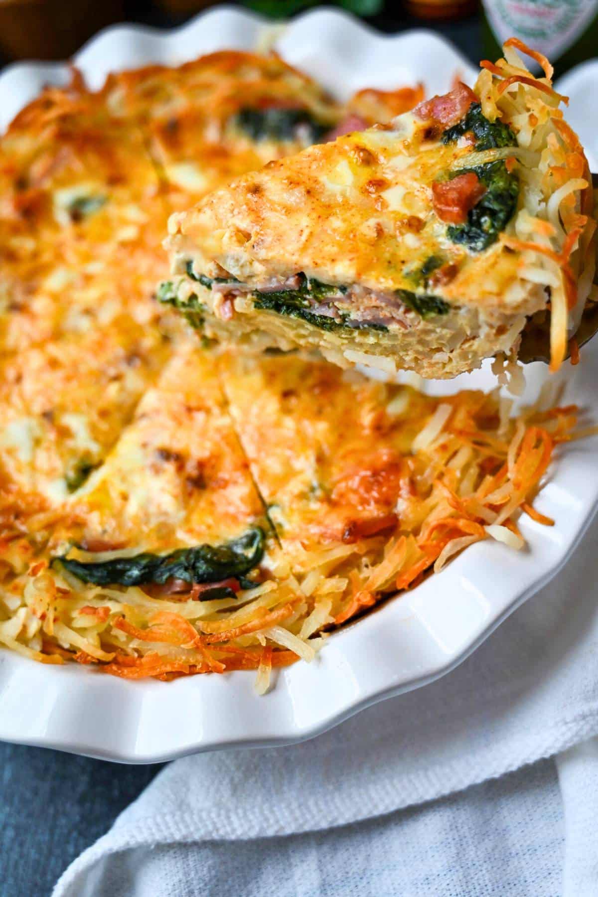 holding up a slice of hashbrown crust quiche