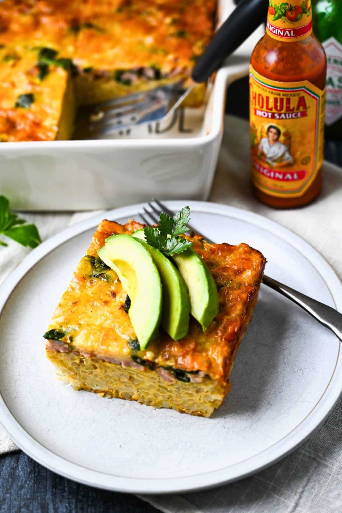 a slice of healthy hashbrown casserole on a plate with avocado slices