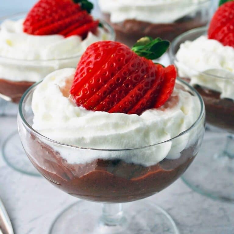 dishes of chocolate protein pudding with whipped cream and strawberry on top