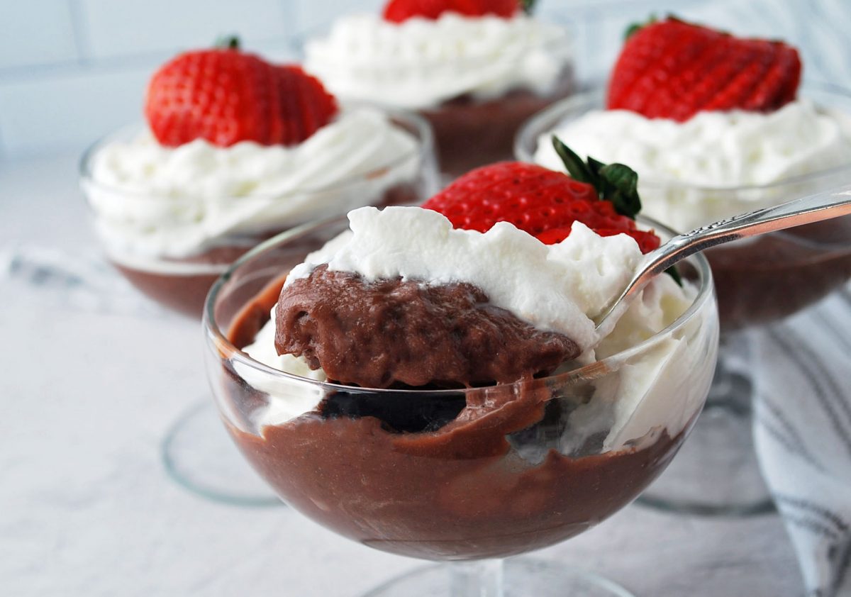 spoonful of pudding with parfait glasses of pudding parfaits in the background