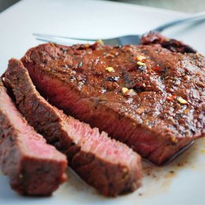 sliced steak on a white plate with a fork