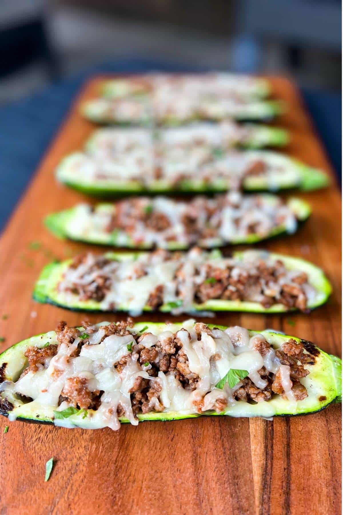 cooked stuffed zucchini boats on a wooden serving board