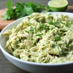 close up of a bowl of avocado chicken salad with fresh lime and cilantro in the background