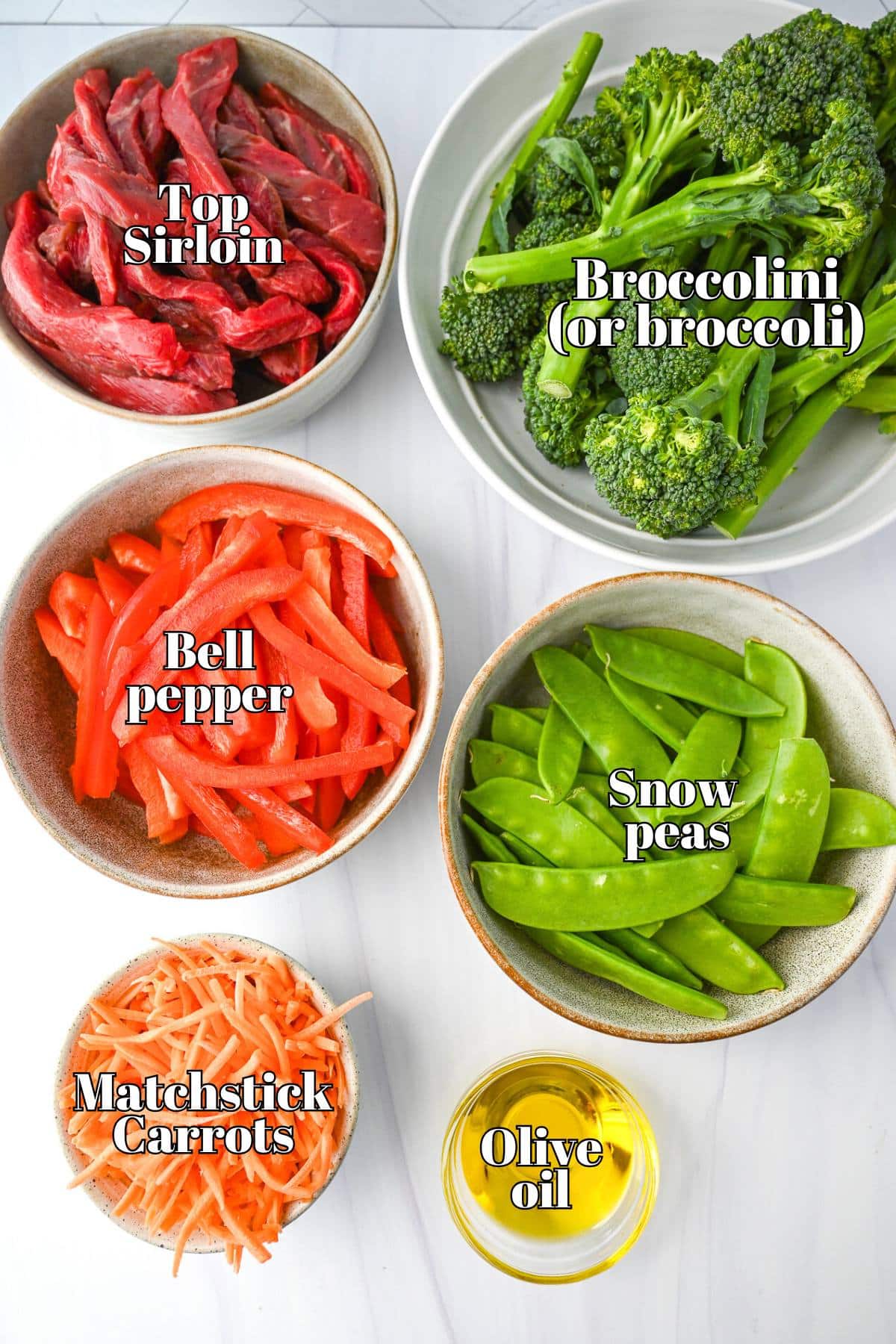 beef and vegetables measured out on a counter for stir fry with a dish of olive oil