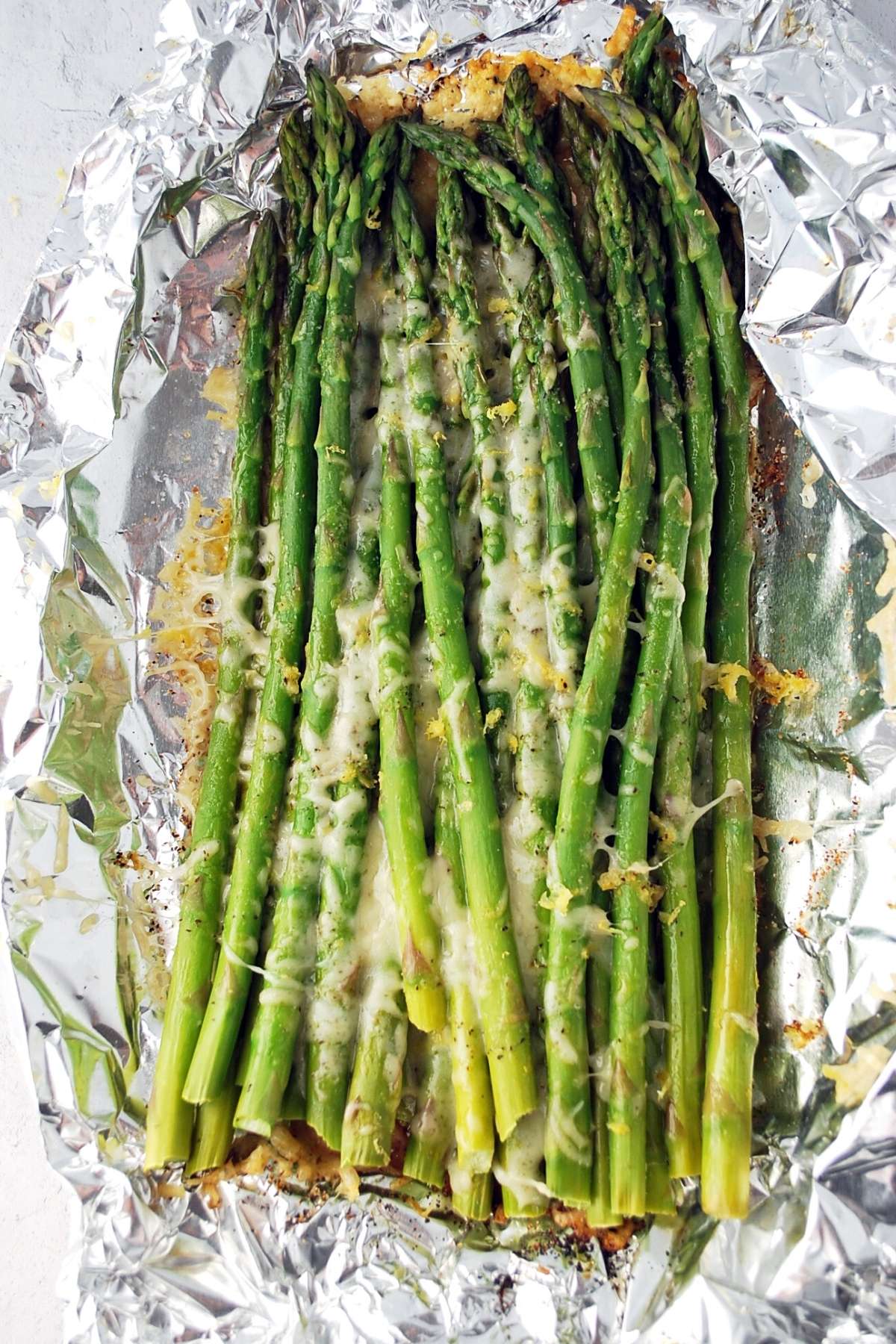 grilled asparagus cooked in a foil packet with melted cheese and lemon zest on top