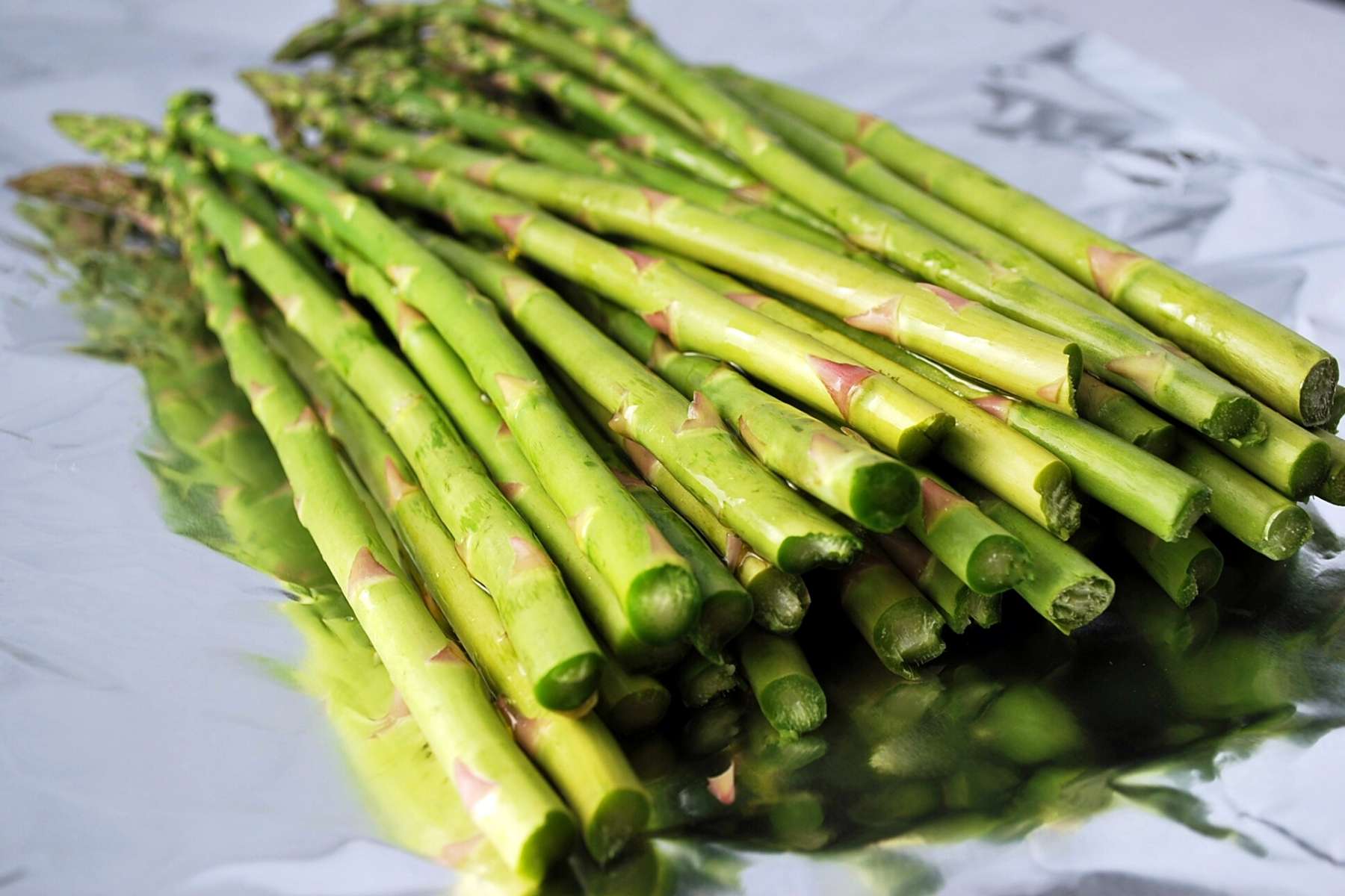 fresh asparagus on a sheet of aluminum foil with ends snapped off