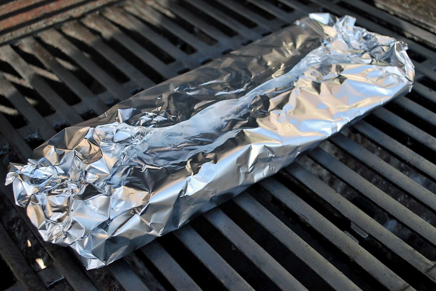 a foil packet of asparagus cooking on a grill