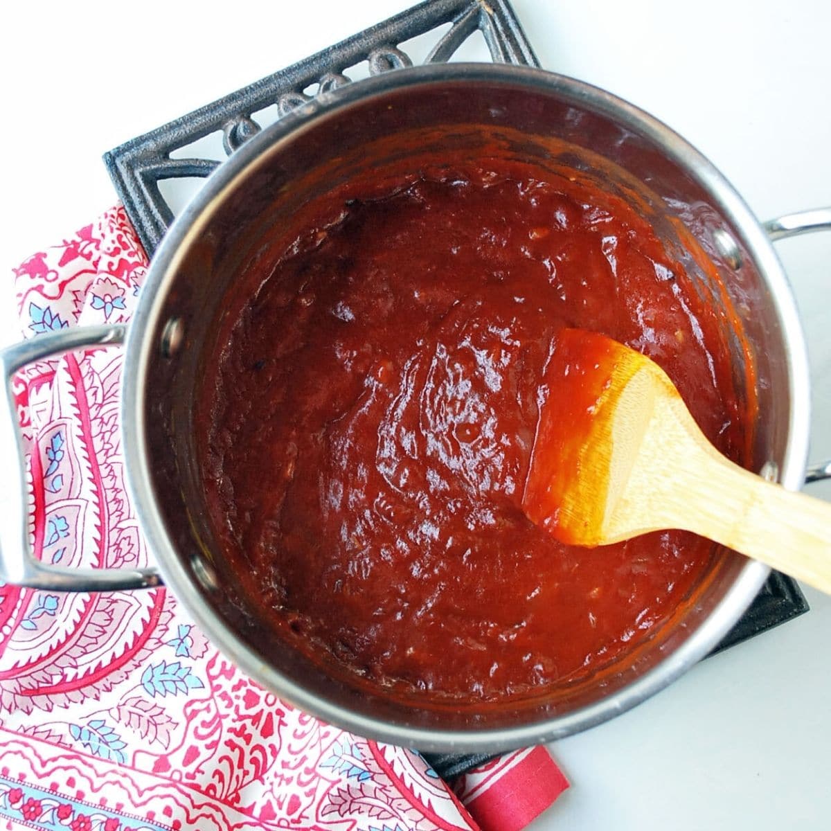 homemade BBQ sauce in a saucepan with a wooden spoon
