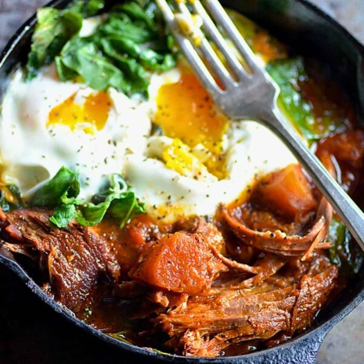 sweet spicy pot roast in a skillet with spinach , eggs, and sweet potato